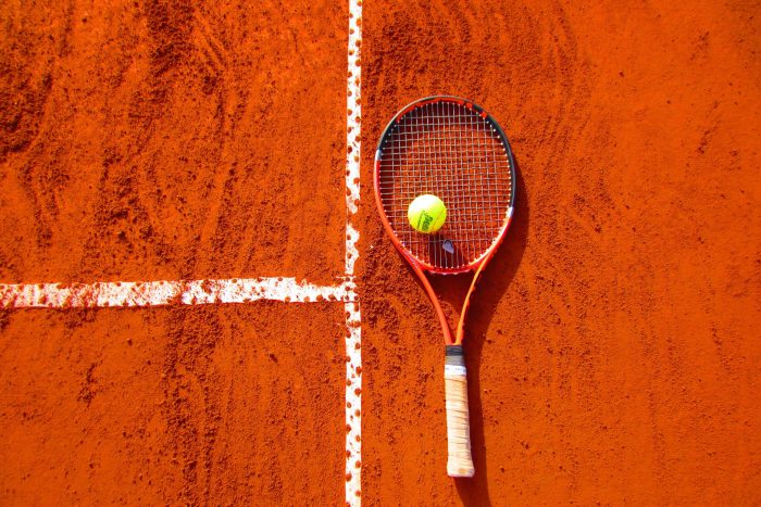 tennisracket op een gravel tennisplein